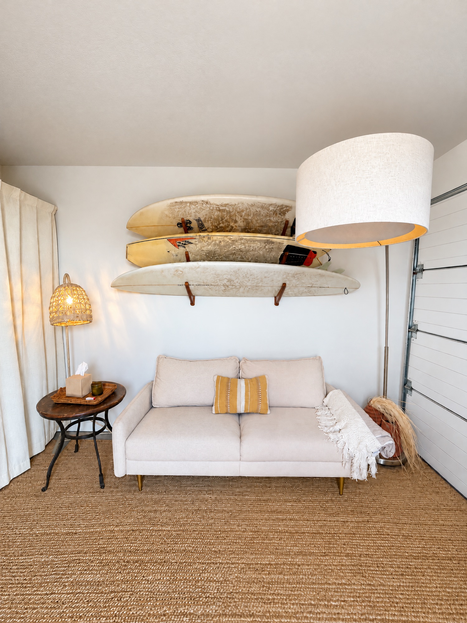The Therapure office: a cream loveseat under three surfboards, a woven rug and a linen curtain